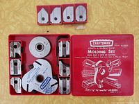 Open red metal Craftsman case showing head and six sets of cutters arranged inside slots
