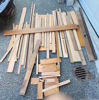 Top-down view of scattered pieces of white oak lumber on pavement, showing a variety of widths and lengths including a long piece nearly 6 feet.