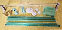 Clear glass rod mounted on metal brackets along with jadeite and blue glass rods laid out beside green ceramic rod holders, white ceramic covers, and green ceramic soap dish.