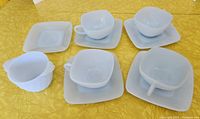 Top angle showing all 4 teacups on saucers plus the sugar bowl and spare saucer on yellow tablecloth