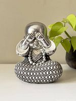 Front view of Buddha statue with hands covering eyes, silver face, and detailed patterned robe in black and white.