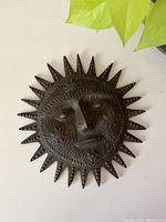 Front view of vintage cast iron sun wall hanging showing detailed facial features and sun rays with textured pattern.