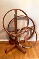 Wooden standing circular loom with multiple circular rings on a floor base.