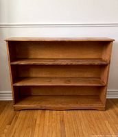 Front view of vintage wooden shelf showing three shelves and decorative bottom edge.