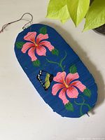 Top down photo of wooden wind spinner with pink flowers and a yellow butterfly painted on a blue background, showing the flat, unspun state.