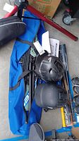 Photo of blue carrying bag holding multiple baseball bats and two black helmets