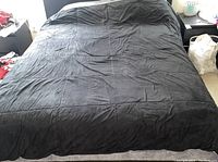 Top-down view of a bed with a large gray blanket spread over it, pillows visible in the background.