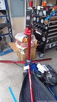 Full view of the red Feedback Sports bicycle work stand set up on concrete floor showing tripod base and clamp.