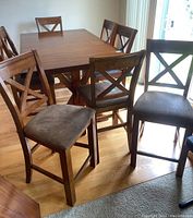Set of eight wooden counter height dining chairs with upholstered seats arranged around a wooden dining table, showing overall condition and matching design
