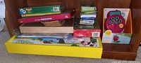 Shelf with various kids educational games and toys stacked horizontally including preschool learning books, Memory and Get Ready Preschool games, and a large yellow box labeled Imaginarium Learning.