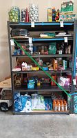 Full front view of metal storage rack filled with various household items for size reference, showing the shelving structure and five shelves.
