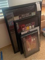 Black photo and poster frames stacked, visible sizes 18x24, 13x19, with other smaller frames.