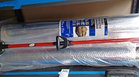 Two rolls of reflective insulation stacked with visible label, alongside part of red mop and broom handles.