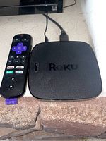 Top view of Roku streaming device and remote showing Roku logo and shortcut buttons on remote