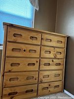 Full frontal view of the wooden dresser showing all 8 drawers with built-in handle cutouts and natural wood finish.