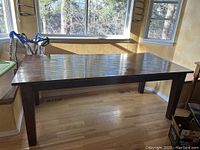 Photo showing the entire wooden kitchen table with visible varnish damage area in the center of the tabletop.