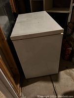Image of the white stand alone chest freezer showing top and one side of the unit.
