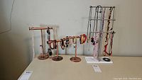 Full view of four jewelry stands holding various necklaces and bracelets including beaded bracelets and necklaces.