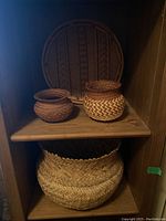Four hand woven baskets arranged on wooden shelves showing size and shape variety.