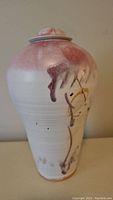 Side view of ceramic jar showing abstract pink and purple glaze on white base with brush stroke designs in yellow and purple.