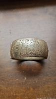 Top view showing detailed floral engraving on wide sterling silver bangle bracelet.