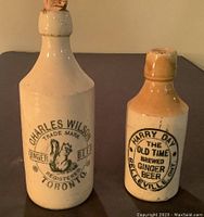 Frontal view of both ceramic ginger beer bottles showing branding and corked tops.