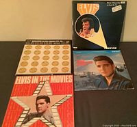 Four Elvis Presley LP records laid out on dark surface with front covers visible.