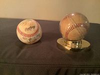 Photo showing two autographed baseballs, one on a gold stand