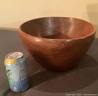 Photo of large Danish teak wood bowl next to a soda can for size comparison, showing rounded shape and smooth surface.