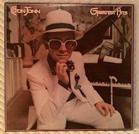 Front cover of Elton John Greatest Hits vinyl album showing Elton John in white suit and hat.