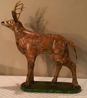 Full side view of folk art deer statue showing detailed antlers and body texture