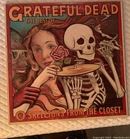 Front cover of Grateful Dead Skeletons From The Closet LP showing colorful illustrated artwork with a woman and a skeleton.