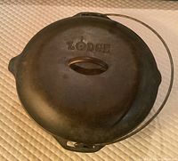 Top view of the closed Dutch oven with lid on, showing the 'Lodge' embossed logo on the lid and the bail handle.