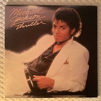 Front cover of Michael Jackson Thriller vinyl album showing Michael Jackson in white blazer on black background.
