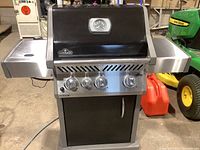 Front view of closed grill showing black hood, integrated thermometer, control knobs and side shelves