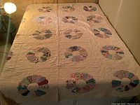 Full view of the quilt laid flat on a bed, showing multiple Dresden plate blocks spaced evenly across the surface on a light background.