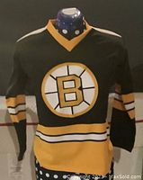 Front view of vintage Boston Bruins black and gold hockey jersey with circular 'B' logo and striped sleeves and waist.