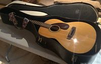 Yamaha FG-75 acoustic guitar with hard case open, guitar inside showing front and strap