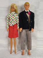 Front view of Barbie and Ken dolls standing together showing their outfits and facial features.