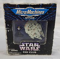 Front view of boxed Millennium Falcon Micro Machines set with visible character figure inside, showing shelf wear on box edges.
