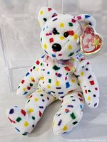Front view of the Ty Beanie Baby Confetti Teddy Bear inside the protective case, showing colorful confetti pattern and attached Ty tag.