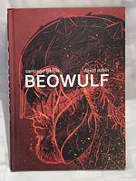 Front cover of the Beowulf hardcover graphic novel showing detailed artwork of a helmeted figure with dark red and black color scheme and text with author names.
