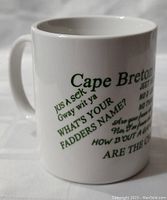 Side view of white ceramic mug showing green text with Cape Breton sayings including 'Cape Breton (Sayings)', 'Jeet Yet?', 'No D' Jou', 'No Twirly', 'What's Your Fadders Name?', 'How B`out a Game of Tarabish?', and 'Are the Cheques In?'.