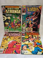 Four vintage Doctor Strange comic books displayed flat, showing full front covers with colorful artwork and titles.
