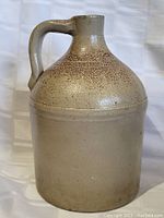 Front view of large early stoneware jug showing round base and handle.