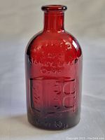 Front view of deep red glass bottle embossed with 'FRANKS SAFE KIDNEY LIVER CURE' and Wheaton Glass logo at base.