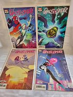 Four Ghost Spider comic books arranged on a white background, showing full covers featuring Ghost Spider and other characters with vibrant colors.
