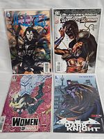Four comic books displayed side by side showing covers: Justice League Dark No. 11, Blackest Night Wonder Woman No. 1, Women of Marvel Variant No. 1, Batman The Dark Knight No. 11.