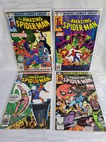Full view of all four vintage Amazing Spider-Man comics in protective sleeves, displayed upright on a white surface.
