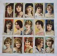 Photo of 15 vintage tobacco cigarette cards arranged in rows, showing female portraits with varied backgrounds and attire.